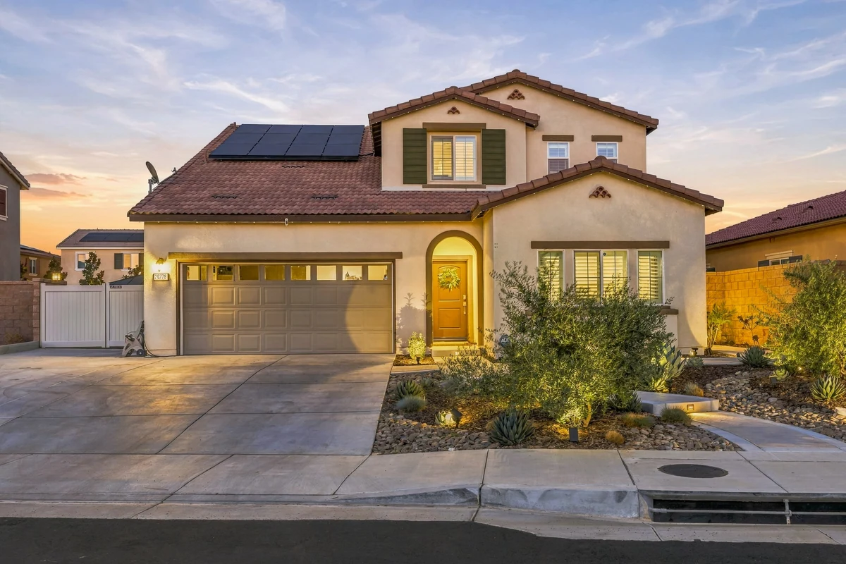 Two-story home with a garage, landscaped entry and rooftop solar panels at dusk