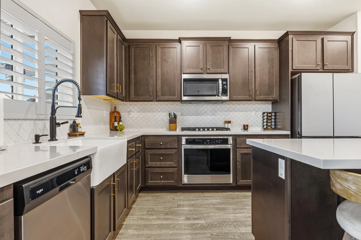 Dark wood kitchen cabinets with stainless steel appliances and pale countertops
