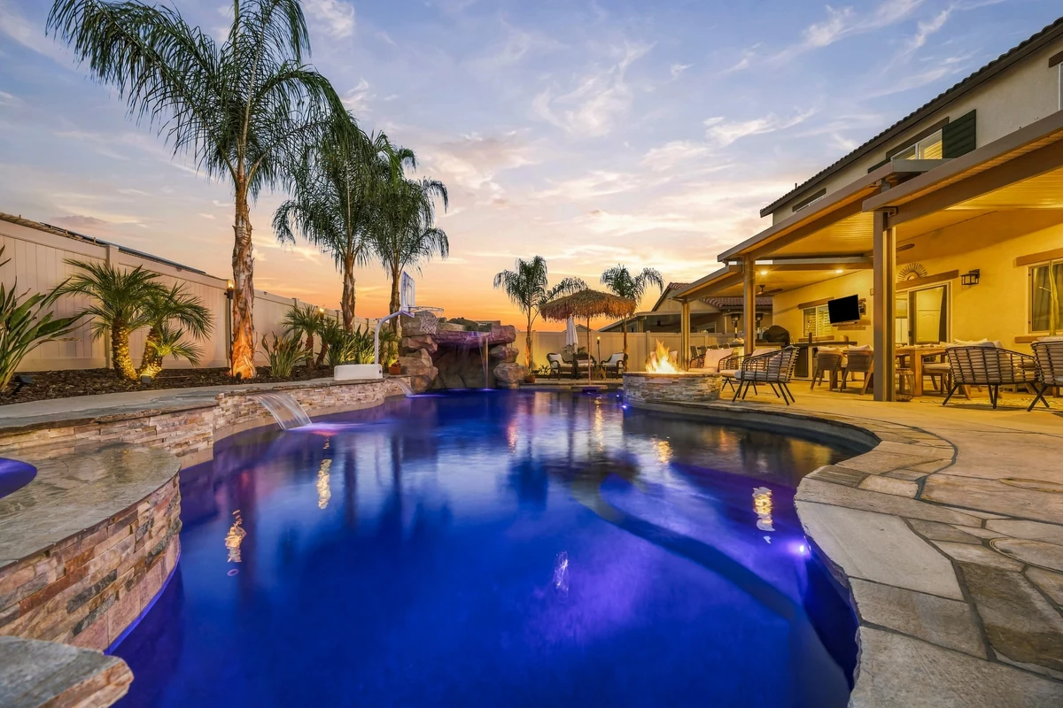 Curving pool reflecting dusk light with palm trees and a covered terrace