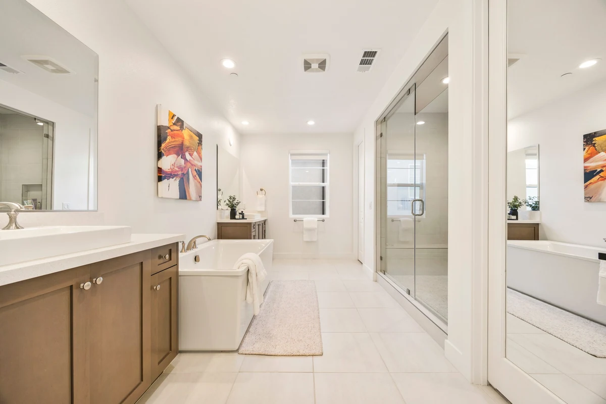 Long bathroom with a double vanity, freestanding tub and glass shower