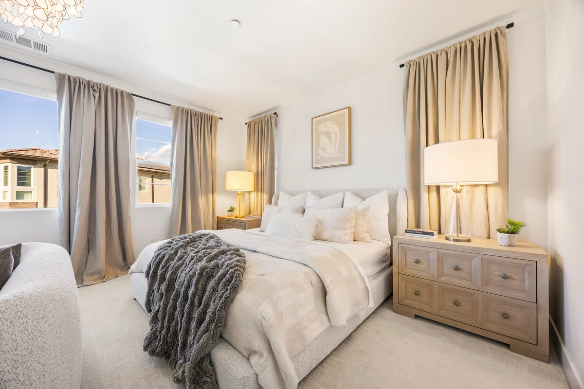 Bedroom with a white upholstered bed, layered curtains and matching bedside lamps