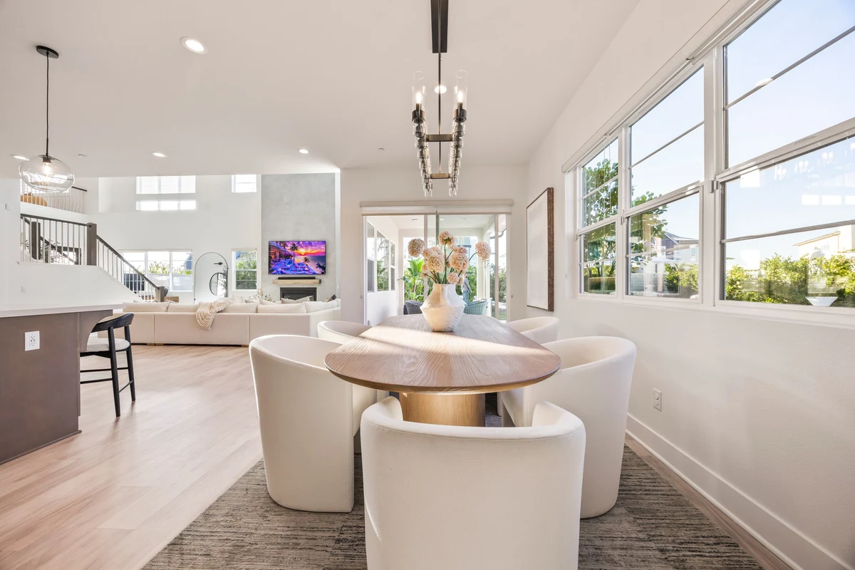 Round dining table and upholstered chairs beside tall windows