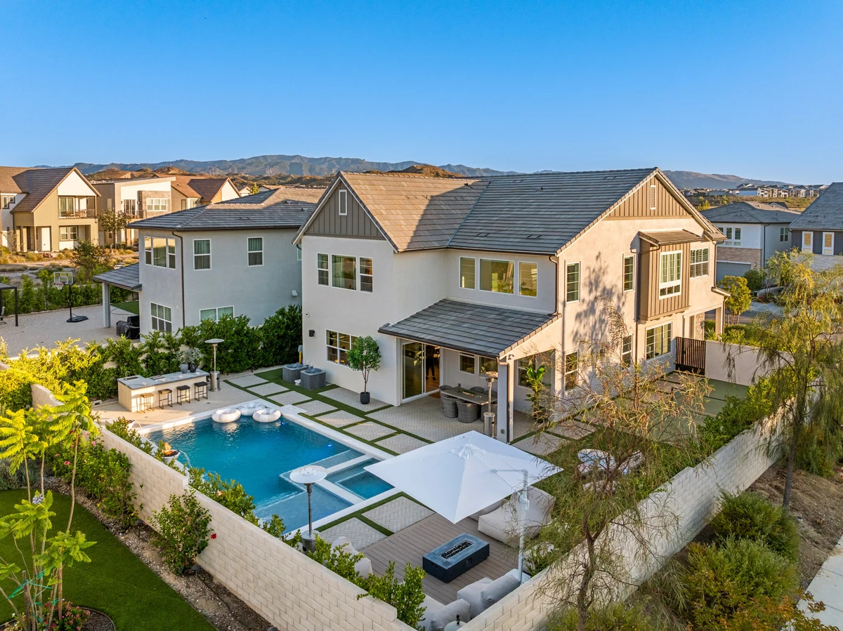 Aerial view of a two-story home, rectangular pool and furnished backyard terrace