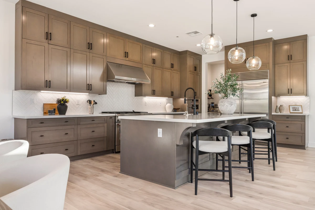 Kitchen island with bar stools, wood cabinetry and glass pendant lights