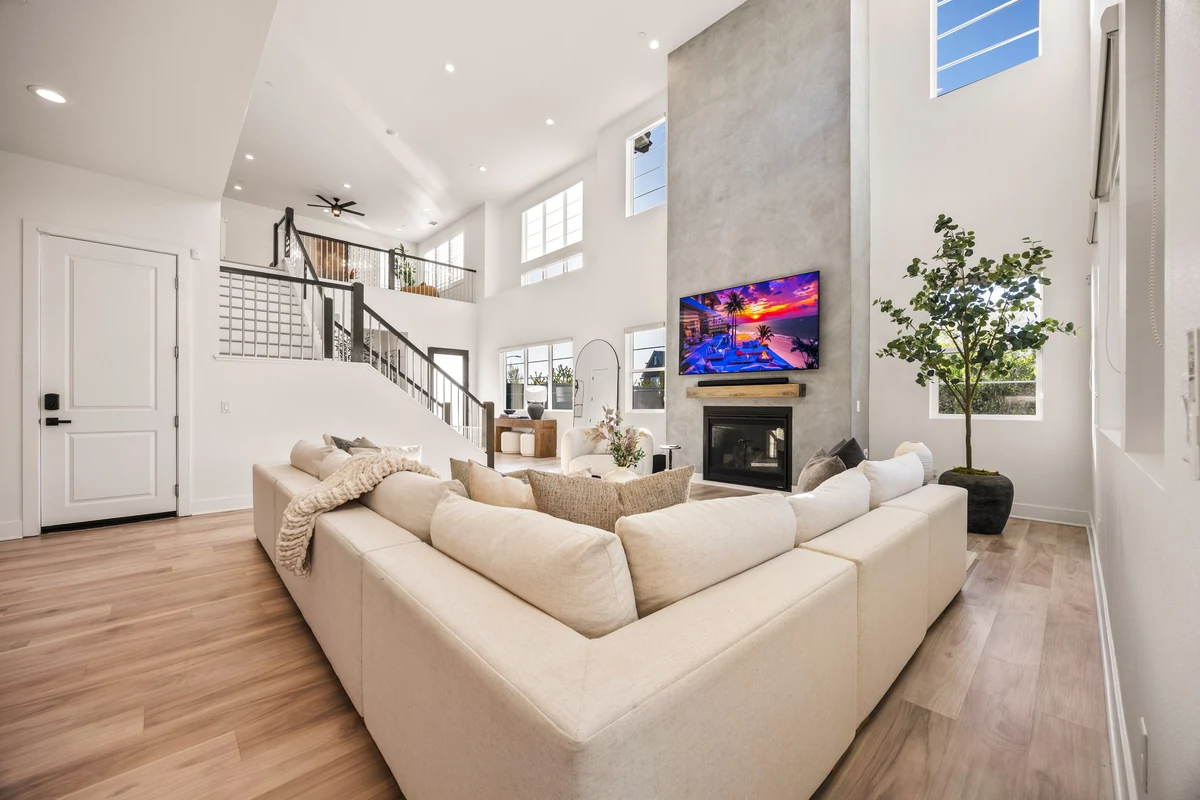 Cream sectional facing a tall fireplace beneath an upstairs railing
