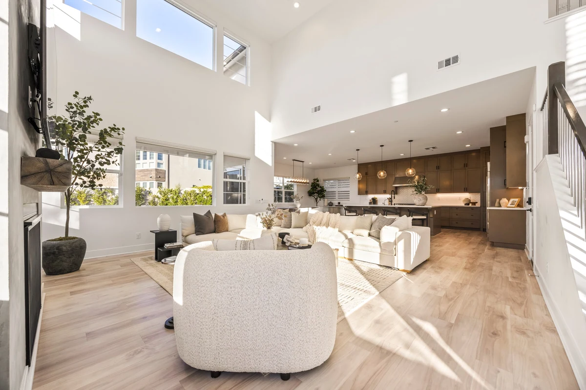 Sunlit double-height living area opening to a kitchen with a large island