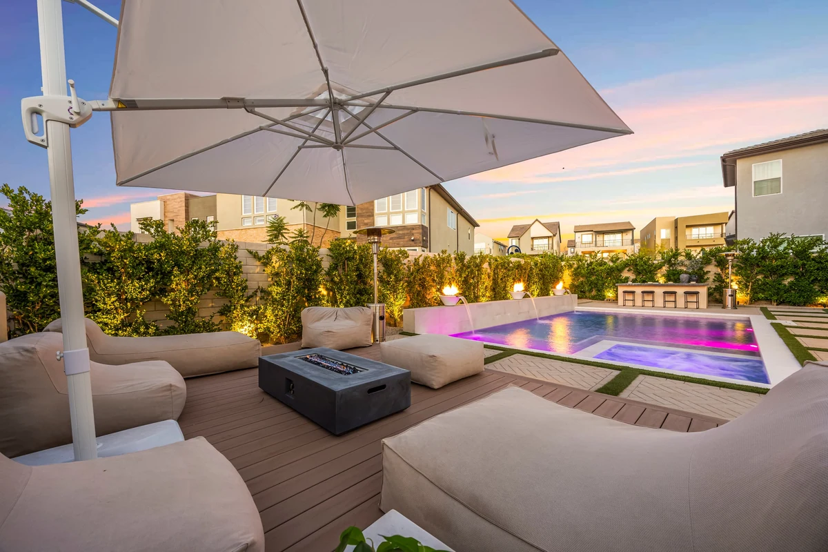 Outdoor sectional and large umbrella beside the illuminated pool