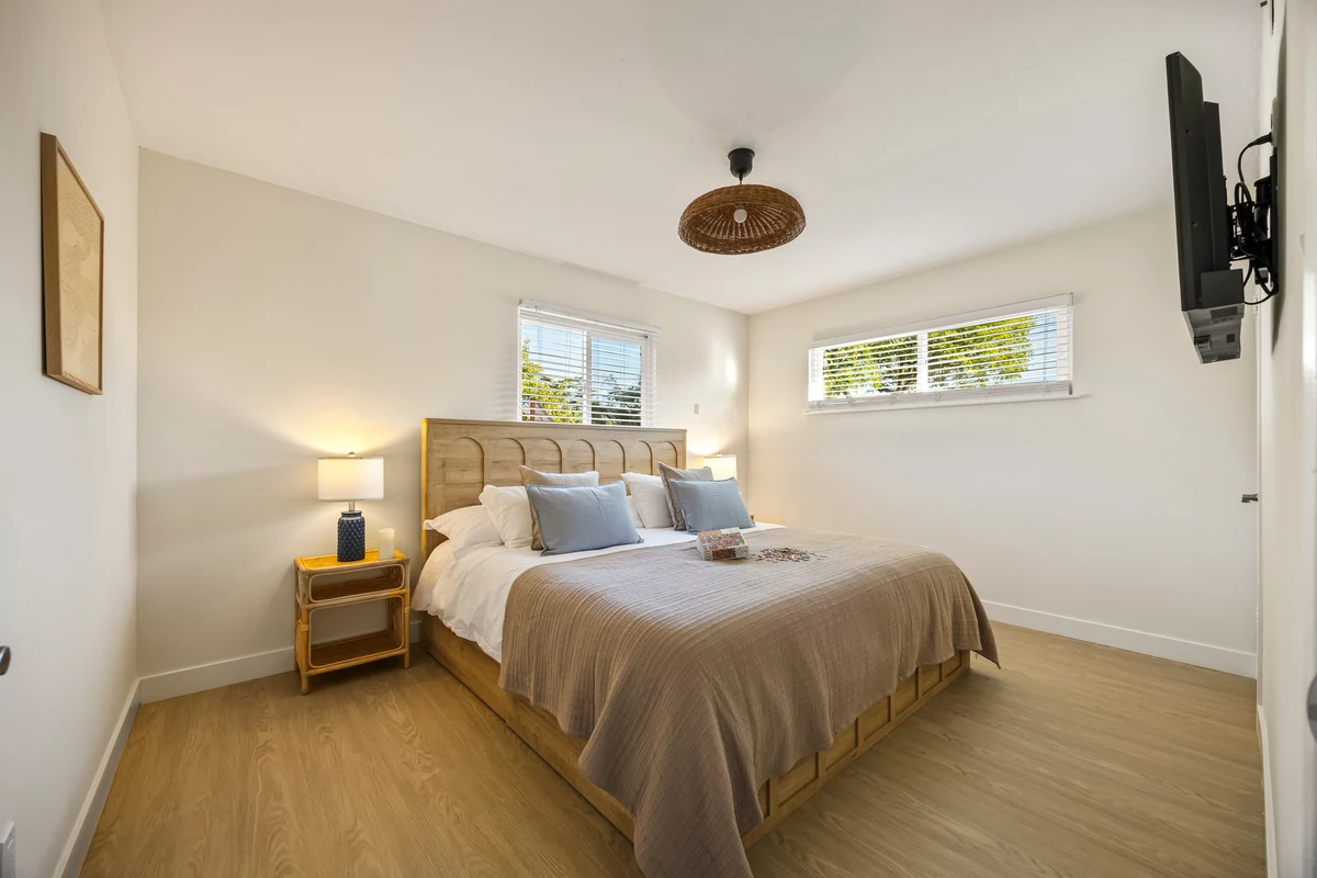 Bedroom with a wooden headboard, high windows and a bedside lamp