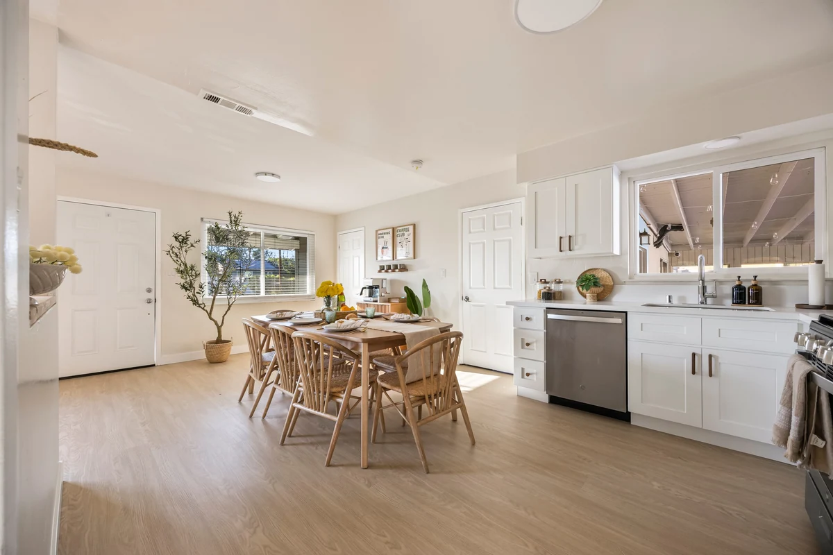 White kitchen cabinets and a wooden dining table in a bright open room